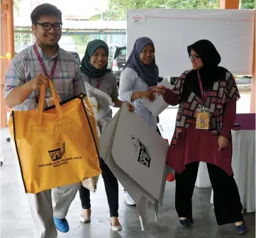  ??  ?? Head of polling centre Ahmad Azmir Hamzah (left) together with other Election Commission personnel taking out the ballot box upon completion of the N27 Balakong by-election early voting at Seri Kembangan police station. — Bernama photo