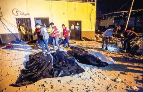  ?? MAHMUD TURKIA/AFP ?? Emergency workers recover bodies after an airstrike killed more than 40 at Tajoura Detention Centre, east of Tripoli, early on Wednesday.