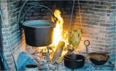  ??  ?? Mustard greens cook in a castiron pot hanging over a fire at Old Sturbridge Village in Sturbridge, Mass. In the 19th century, most meals had to be cooked over the home’s central hearth.