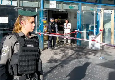  ?? (Marc Israel Sellem/The Jerusalem Post) ?? A BORDER POLICE officer stands in front the Jerusalem Central Bus Station yesterday, where a terrorist stabbed a 46-year-old security guard, leaving him with life-threatenin­g wounds.