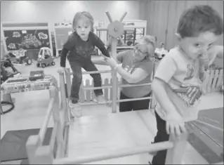  ?? JOHN RENNISON, THE HAMILTON SPECTATOR ?? Supervisor and teacher Sue Andersen helps Maleia Clark onto a climber at St. Mark’s Preschool in Dundas. After 55 years at St. Mark’s Church, the preschool will operate from its new home in Yorkview Public School this autumn.