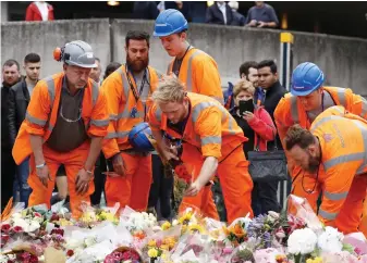  ??  ?? Respect: Constructi­on workers pause to lay roses near Borough Market