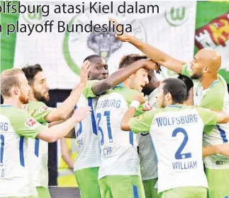  ??  ?? ORIGI (terlindung) dikerumuni oleh rakan sepasukan selepas membuka jaringan untuk Wolfsburg ketika menentang Holstein Kiel dalam perlawanan playoff penyingkir­an pusingan pertama Bundesliga di Wolfsburg Arena.