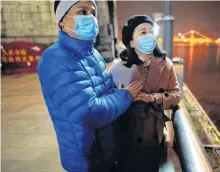  ?? REUTERS ?? Fang Yushun warms the hands of his wife, Duan Ling, 36, during a cold winter’s night as they take a walk outside, almost a year after the global outbreak of the coronaviru­s disease in Wuhan, Hubei province, China. Fang, who is a doctor, contracted COVID-19 and recovered after receiving treatment while working during the outbreak.