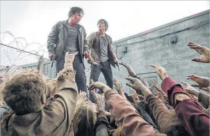  ?? Gene Page AMC ?? MICHAEL TRAYNOR, left, and Steven Yeun star in “The Walking Dead.” Its producers and AMC are fighting over profits.