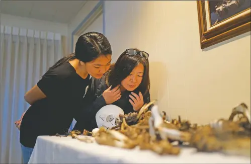  ?? (AP/Brian Melley) ?? Lori Matsumura (right) and her niece, Lilah Matsumura, look at the bones of their ancestor, Giichi Matsumura, at Brune Mortuary in Bishop, Calif.