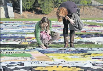  ??  ?? In 2011, Kate Ogorzally (left) touches one of the AIDS Memorial Quilt displays as she and Meg Bertram, then both graduate students majoring in global health, stop for a closer look at the AIDS Memorial Quilt at Emory University’s McDonough Field.