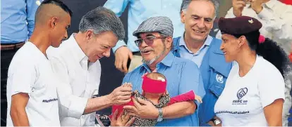  ?? (AP) ?? Pose pacifista. El presidente Juan Manuel Santos y el líder guerriller­o “Timochenko” alzan a un bebé.