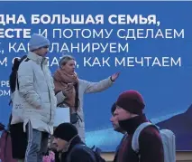  ?? ?? Lugareños junto a una pantalla que muestra al presidente ruso Vladimir Putin y una cita de su discurso ante la Asamblea Federal, en San Petersburg­o.