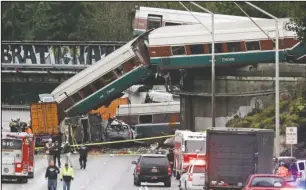  ?? The Associated Press ?? AMTRAK DERAILMENT: Cars from an Amtrak train lie spilled onto Interstate 5 below alongside smashed vehicles as some train cars remain on the tracks above Monday in DuPont, Wash. The Amtrak train making the first-ever run along a faster new route...