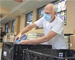  ?? RONDONE/THE COMMERCIAL APPEAL JOE ?? Jim Mccoid prepares food boxes inside St. Anne Church that are given away Monday through Thursday every week for low-income families in need.