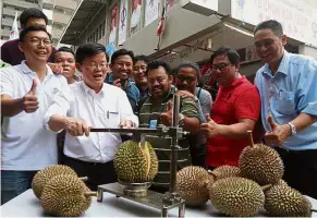  ??  ?? Local delight: Chow (second left) hosting a durian party with media members at his service centre at Jalan Kedah in George Town.