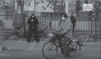  ?? NG HAN GUAN/AP ?? A RESIDENT ON BICYCLE past by security personnel outside the U.S. Embassy in Beijing, China on Nov. 16.