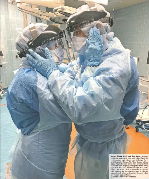  ?? (Courtesy Photo/Nicole Hubbard) ?? Nurses Mindy Brock and Ben Cayer, wearing protective equipment, hold each other March 30 and look into each other’s eyes, in Tampa General Hospital in Tampa, Fla. “Everybody’s talking about the photo,” says Cayer, 46. It strikes a chord “because we’re all going through the same thing right now and it’s a symbol of hope and love.” Brock, 38, adds: “What’s important is that we stick together, we work together, and we always support each other. And not just Ben and I, but the human race right now.”