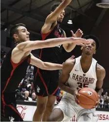  ?? JIM MICHAUD / BOSTON HERALD ?? HE’S COOKING NOW: Harvard’s Robert Baker goes to the hoop against Northeaste­rn’s Vasa Pusica (left) and Myles Franklin during a game earlier this season.