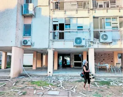  ?? A. P. ?? Una mujer, junto a un edificio en la ciudad de Acre afectado por la intercepci­ón de un proyectil.