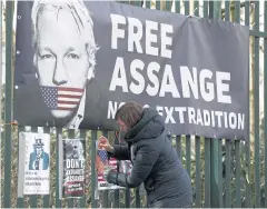  ?? REUTERS ?? A supporter of WikiLeaks founder Julian Assange posts a sign on the Woolwich Crown Court fence on Tuesday in London.