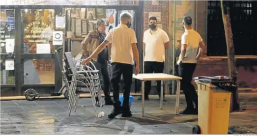  ?? JUAN CARLOS MUÑOZ ?? Camareros recogiendo las sillas y mesas de un bar de la calle San Jacinto cuando el cierre de los bares estaba decretado a las diez de la noche.