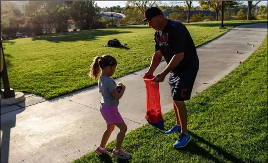  ??  ?? Hailey Dawson and coach Tom Hallett gather baseballs Thursday at Anthem Hills Park. Dawson is preparing to throw the first pitch at Game 4 of the World Series.