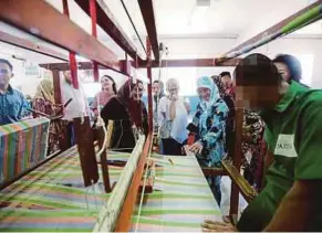  ??  ?? Tengku Puan Pahang Tunku Azizah Aminah Maimunah Iskandaria­h looking at the fabric being woven by inmates.