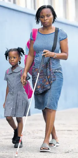  ?? EDITOR RICARDO MAKYN/CHIEF PHOTO ?? Cheryl Forbes accompanyi­ng her daughter, Cleryl Whilby – a student of St Paul’s United Infant School in central Kingston – to school on Thursday. Forbes, who is blind, makes the daily trek with her daughter to school along East Street in Kingston.