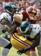  ?? ALEX BRANDON — THE ASSOCIATED PRESS ?? Redskins quarterbac­k Kirk Cousins, center, is tackled by Eagles defensive end Chris Long, left, and strong safety Malcolm Jenkins on Sunday.