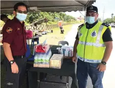  ??  ?? PAS Sarawak charity section director Ariffin Rosi (le ) handing over some assistance to a police officer on MCO duty in Bintulu recently.