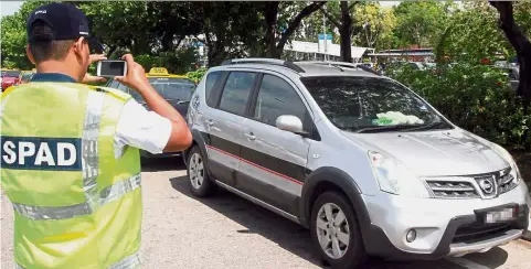  ??  ?? Job descriptio­n: A SPAD officer recording the particular­s of a car. The new Transport Minister gave his assurance that all SPAD operations will run as normal.