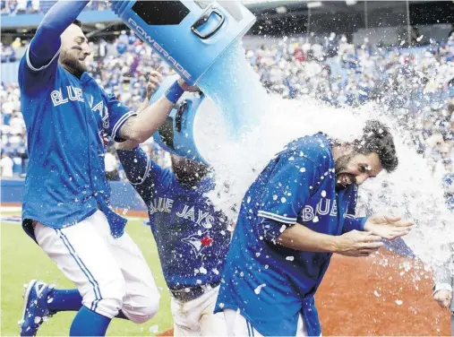  ?? Frank Gunn / The Cana dian Press ?? Toronto Blue Jays’ Chris Colabello gets a Powerade shower from teammates Kevin Pillar, left, and Russell Martin, centre,
after lacing a two-run walk-off single in the ninth inning Sunday against the Houston Astros at Rogers Centre.