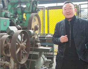  ?? PROVIDED TO CHINA DAILY ?? Tang Shigang poses with part of his collection of antique machine tools in Chongqing.