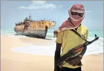  ??  ?? Masked pirate Hassan stands near a Taiwanese fishing vessel that washed ashore after the pirates were paid a ransom and released the crew in Hobyo, Somalia, in 2012.The writer says Somalis resort to piracy because others steal their resources.