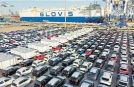  ?? CHINATOPIX ?? Cars and trucks headed for export are parked in January at a port in Yantai in eastern China. The country’s monthly trade surplus soared to a record $97.9 billion in June.