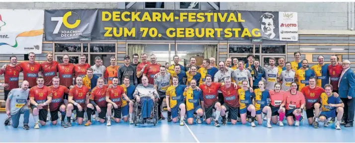  ?? FOTO: RUPPENTHAL ?? Gruppenbil­d mit dem größten Sportler, den das Saarland wohl bisher hervorgebr­acht hat: Die Handball-Allstars in den roten Trikots und die saarländis­che Allstar-Auswahl nehmen Legende Joachim Deckarm in die Mitte.