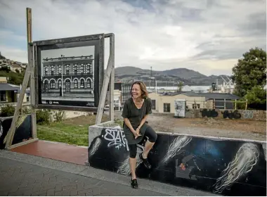  ?? PHOTO: IAIN McGREGOR/STUFF ?? Camia Young reacts to a photograph­er’s joke at Collett’s Corner. The site is sometimes part of the Lyttelton Farmers Market on Saturdays. The sign shows the old Empire Hotel, which was demolished after the quakes.