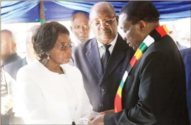  ?? — (Picture by Shelton Muchena) ?? President Mnangagwa hands over the Zimbabwe flag to Mrs Leocardia Chimbandi, widow of national hero Cde John Chimbandi, while Home Affairs Minister Obert Mpofu looks on at the National Heroes Acre in Harare yesterday. — (More pictures and President’s speech on Page 4).