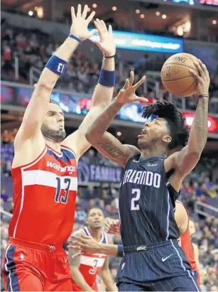  ?? ROB CARR/GETTY IMAGES ?? Elfrid Payton goes to the hoop against Washington’s Marcin Gortat on Friday. Orlando’s loss wasted a nice offensive night from Payton, who finished with a team-high 27 points, 5 rebounds and 8 assists.