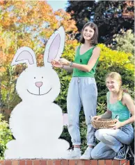  ??  ?? Ear, ear . . . Madeline (17, left) and Annabel (16) Bilkey, of Pacific St, put finishing touches to a bunny at their gate, which their mother Christine Parker cut from an old door, and the girls painted.