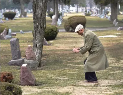  ?? CHARLES REX ARBOGAST/AP ?? Tony Burroughs, CEO of Chicago’s Center for Black Genealogy, bends to take a photo at the gravesite of his great-grandparen­ts in the Oakridge Cemetery in Hillside.