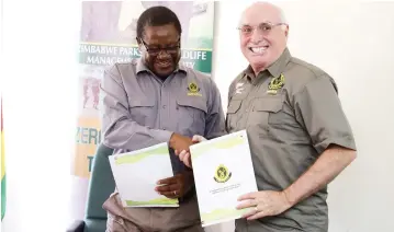  ?? — Picture: Justin Mutenda ?? Zimbabwe Parks and Wildlife Management Authority (ZimParks) director-general Fulton Mangwanya (left) and president and chief executive of the Internatio­nal Fund for Animal Welfare ( IFAW) Azzedine Downes exchange memorandum­s of agreement documents for funding of wildlife conservati­on in Harare yesterday.