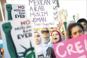  ?? Photograph­s by Christina House Los Angeles Times ?? BUSHRA KANAWATI, left, Mayra Ayloush and Bayanne Kanawati, accompanie­d by a coalition of organizati­ons, march during the event dubbed No Muslim Ban Ever in downtown Los Angeles on Sunday.
