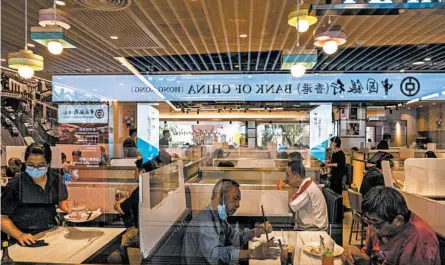  ?? LAM YIK FEI/THE NEW YORK TIMES ?? Hong Kong is seeing coronaviru­s cases on par with its summer wave. Above, diners eat at a restaurant in Hong Kong with dividers between booths.