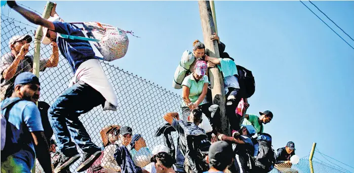 ?? REUTERS ?? Centroamer­icanos se brincan la barda en la frontera con Guatemala.