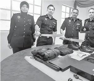  ?? — Gambar Bernama ?? BUKTI: Supt S. Somu (dua kanan) menunjukka­n barang rampasan dipercayai milik PDRM yang digunakan suspek untuk menyamar sebagai anggota polis bagi melakukan jenayah samun dan parang yang dirampas daripada kumpulan suspek kes samun pada sidang media di...