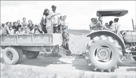  ?? (Ministry of the Presidency photo) ?? Minister of State Joseph Harmon (on trailer with cap) being taken through the village of Itabac in a tractor by residents, to examine the damage caused by the flash flooding due to the overtoppin­g of the Ireng River.