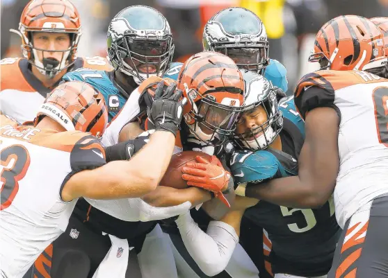  ?? LAURENCE KESTERSON/AP ?? Bengals’Joe Mixon (28) is tackled by Eagles’ Fletcher Cox (91) and T.J. Edwards (57) during the second half on Sunday.