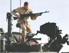  ?? POSTMEDIA NEWS FILES ?? A soldier carries a C6 machine-gun to place on top of a vehicle at the Kandahar Air Base in Afghanista­n.