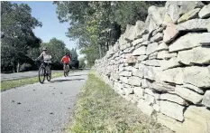  ?? JULIE JOCSAK/POSTMEDIA NETWORK ?? Cyclist's ride past a kilometer-long stonewall in Queenston along the Niagara Parkway.