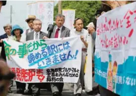  ?? — AFP ?? SAGA: Residents seeking to suspend the operation of No 3 and No 4 reactors of Kyushu Electric Power’s Genkai nuclear plant hold a banner while heading to the Saga District Court.