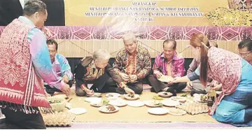  ??  ?? Awang Tengah (centre), flanked by Paulus on his right and Penghulu Ajan, with others performing the ‘miring’ ceremony.