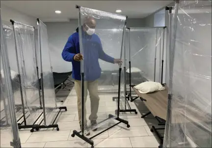  ?? TANIA BARRICKLO — DAILY FREEMAN ?? Tyrone Cooper, the coordinato­r for the Ulster County Warming Center in Kingston, N.Y., demonstrat­es how protective shields are placed up around each cot as part of COVID-19protocol on Wednesday, Dec. 16.